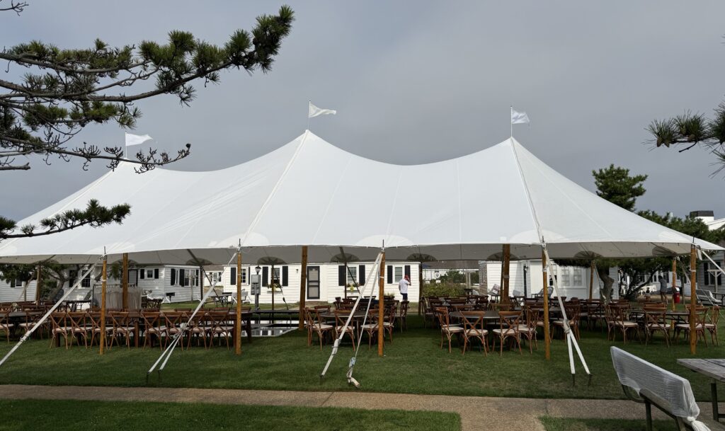 Large sailcloth tent over farm tables and crossback chairs