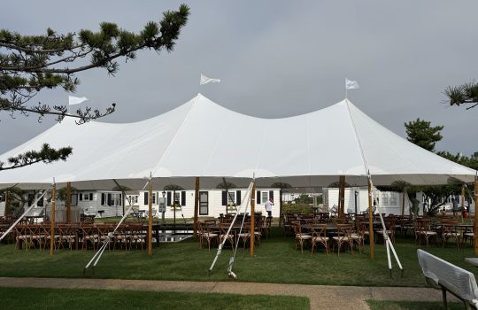 Large sailcloth tent over farm tables and crossback chairs
