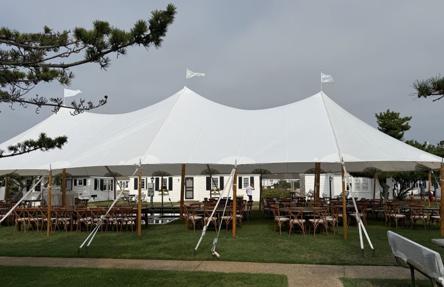 Large sailcloth tent over farm tables and crossback chairs