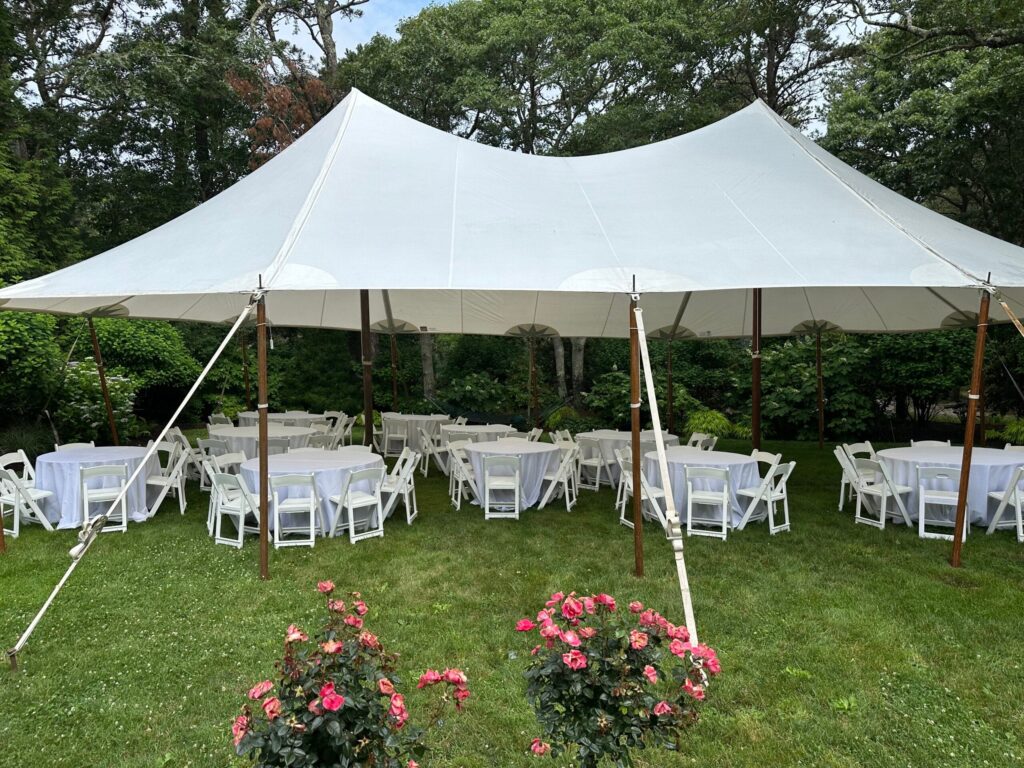 White frame tent over round tables set for an outdoor reception